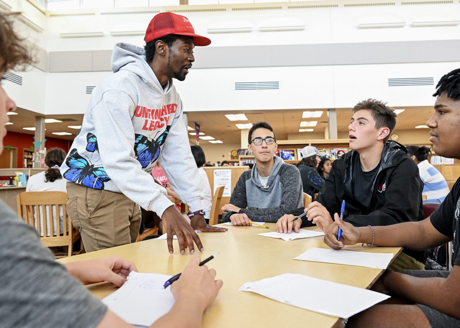 Teacher passionately chatting with students sat at a table together.