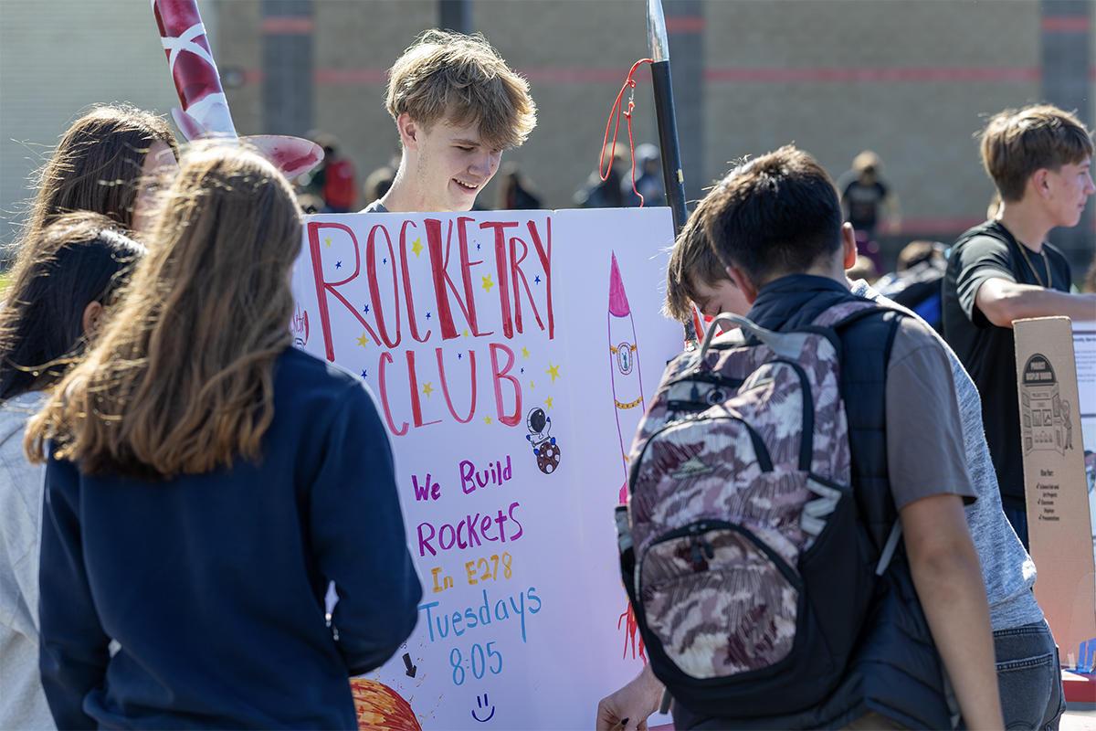 student hokding rocketry club poster at activities fair