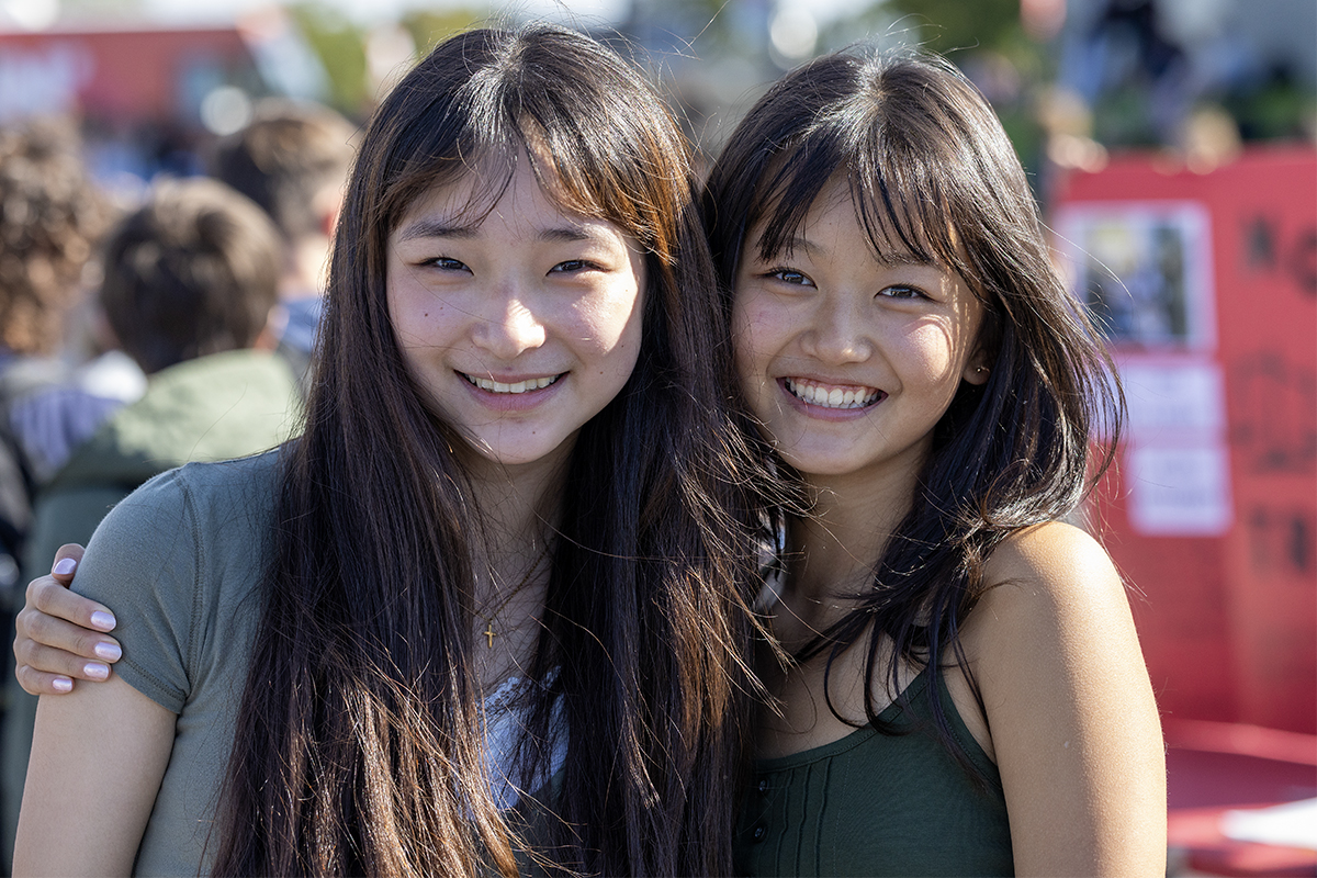 two high school friends smile at activities fair