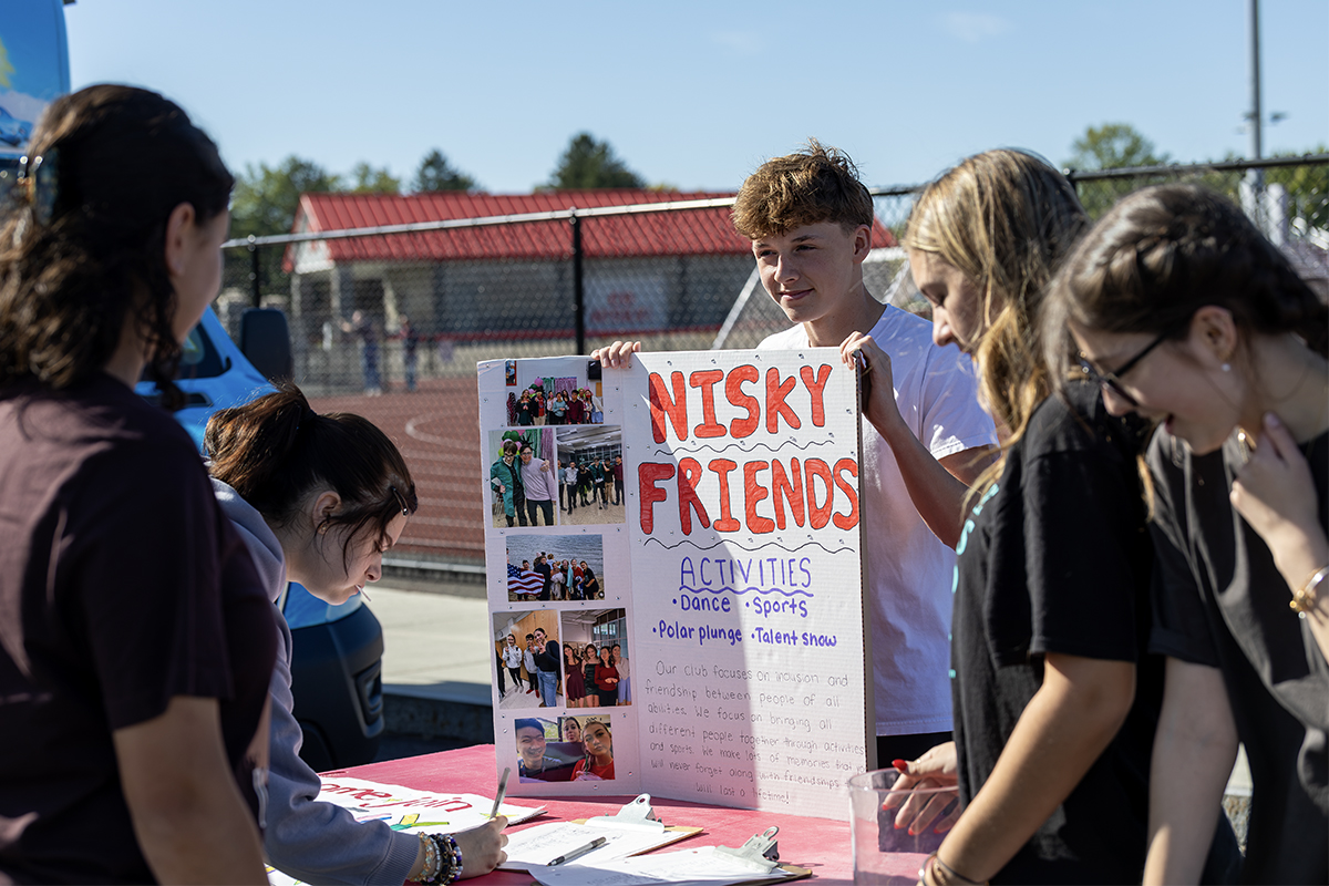 high school student holding a poster that reads Nisky friends at an activities fair