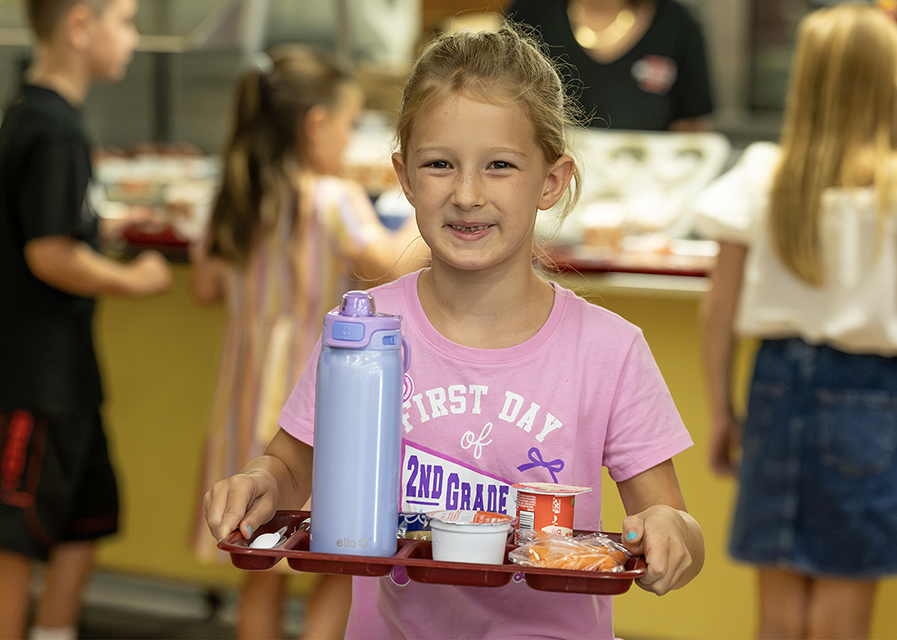 A student carrying a lunch tray.