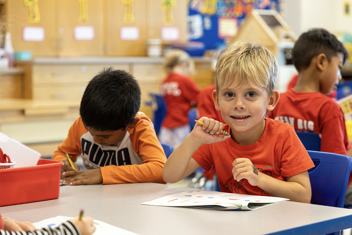 kindergarten student looks up and smiles while working