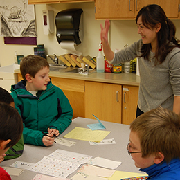 An adult talks to three students in a Craig classroom.