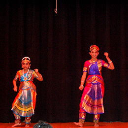 Two students wearing traditional attire dance on the Craig stage.