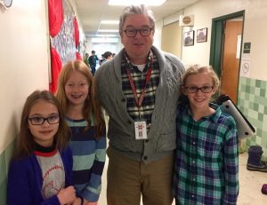 Craig Principal Bill Anders stands in the hallway of the school with three students