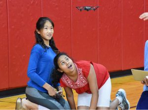 two female students in a gymnasium looking at a drone