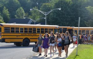 Picture of Iroquois students walking alongside the school toward the main entrance with buses in the background