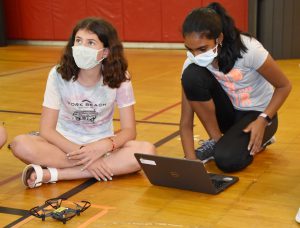 two students working on a laptop and a drone on the gym floor