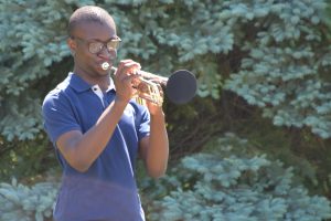 Photo of a student outside playing the trumpet