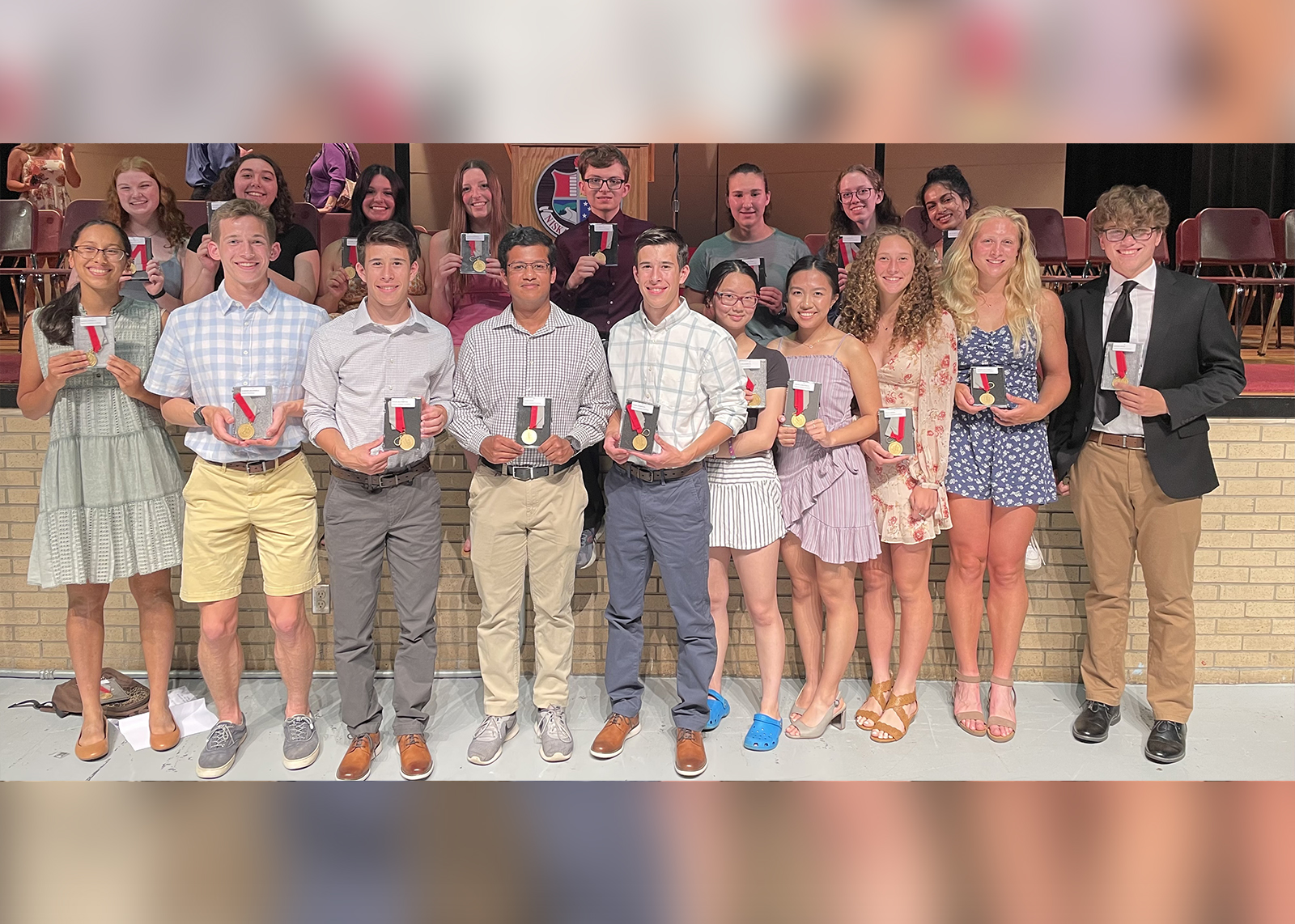 The students who received the 2022 Medal of Academic Excellence pose in the high school auditorium with their medals