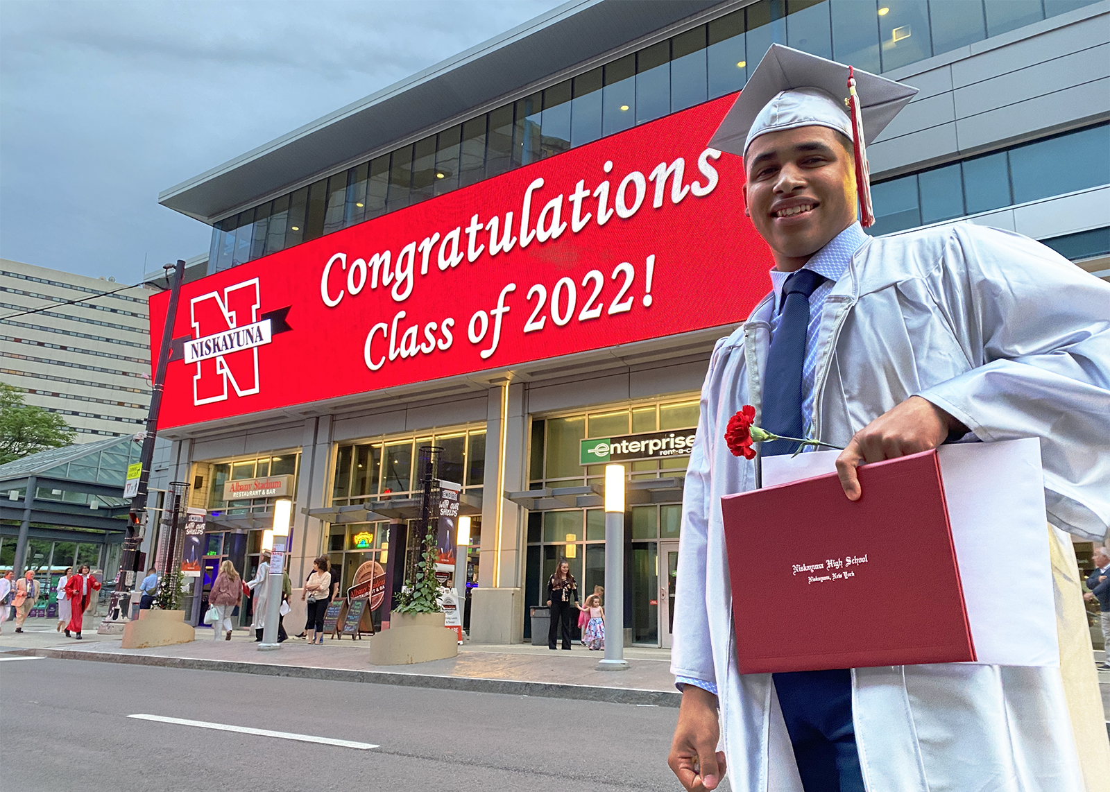 graduate standing in front of marquee