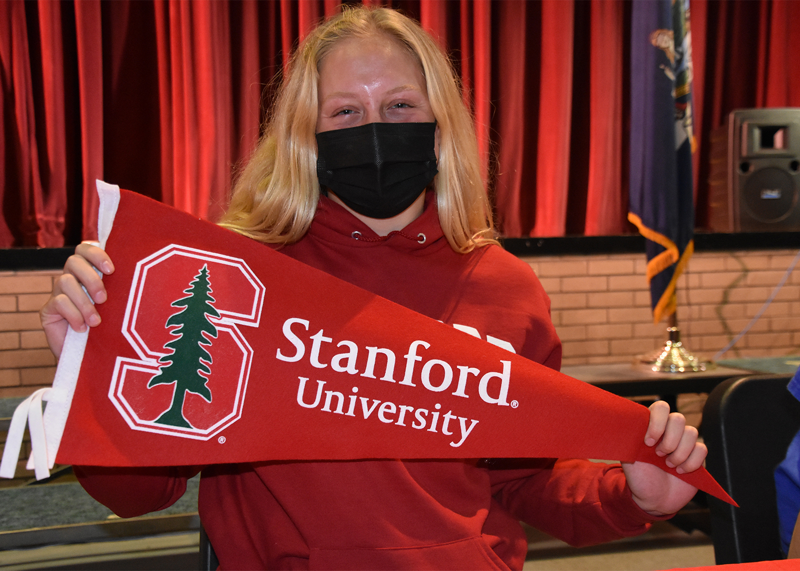 student athlete wearing mask holding pennant