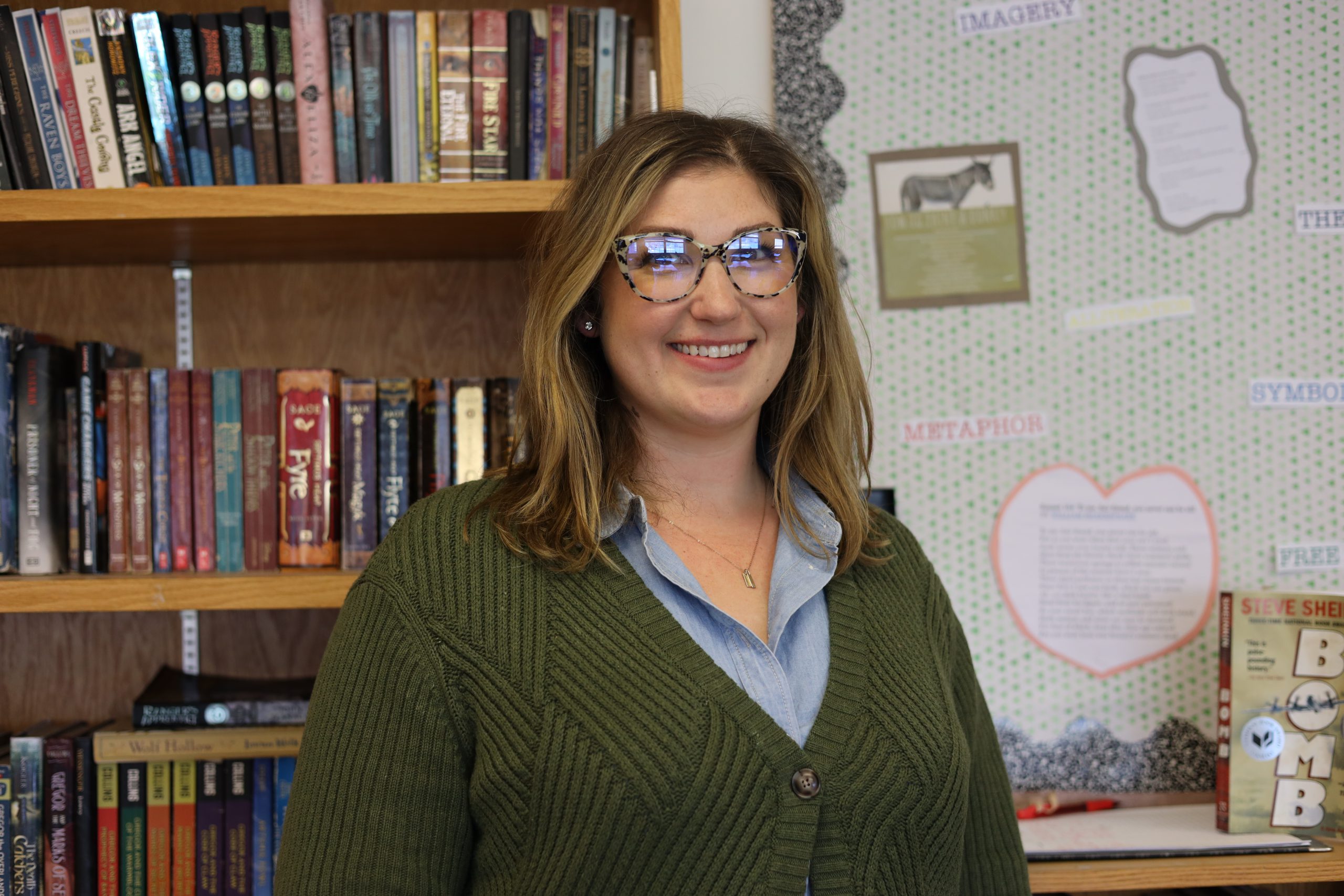 Nancy Czachor standing in front of book shelf and bulletin board. 