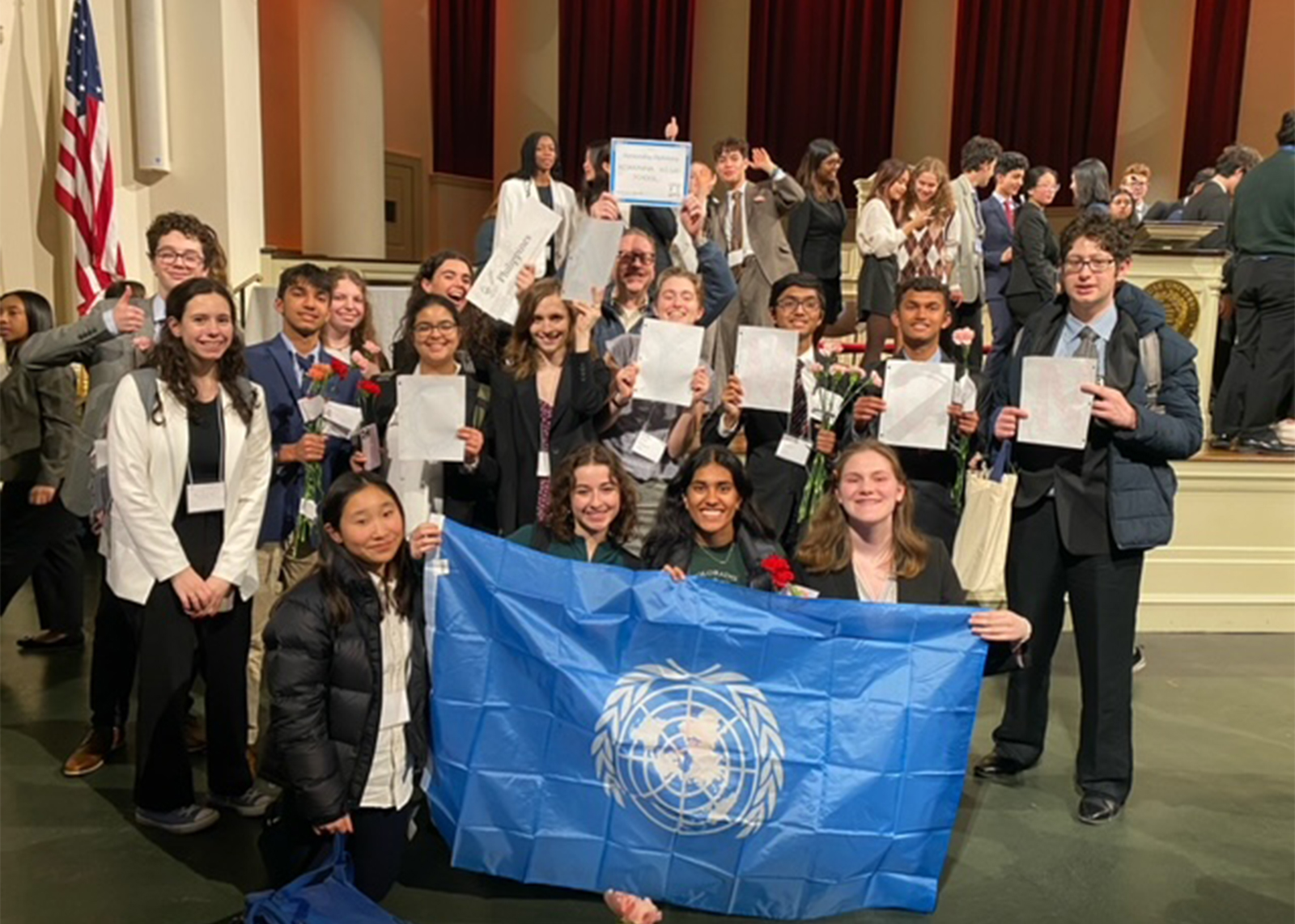 group of students smiling with a model UN flag