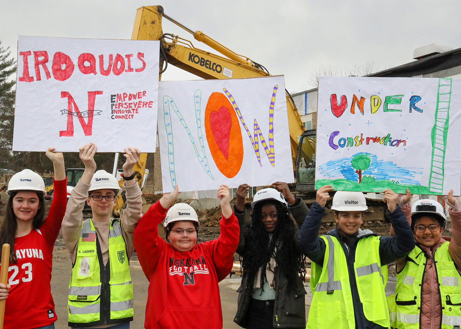students, superintendent and principals at capital project site holding sings that say Iroquois now under construction