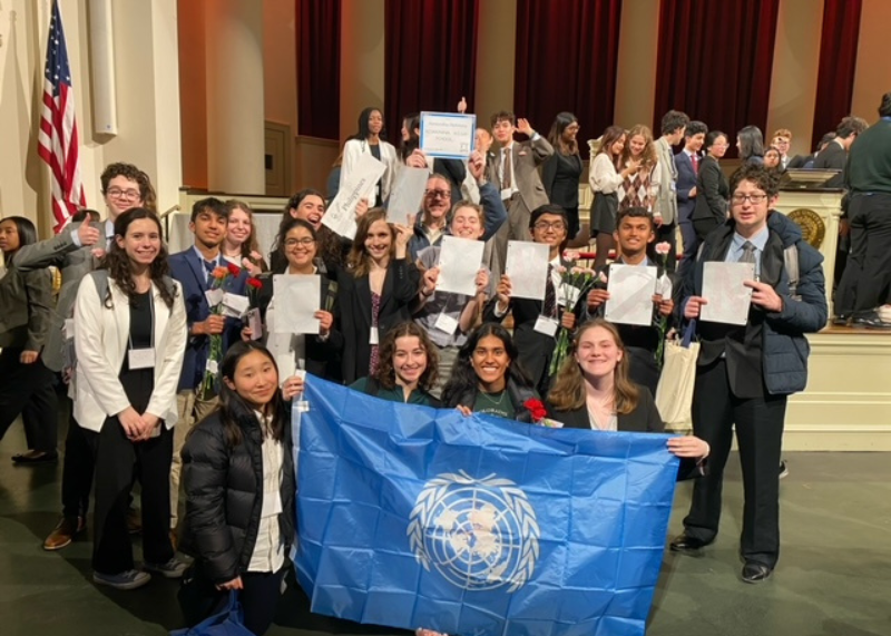 group of students smiling with a model UN flag