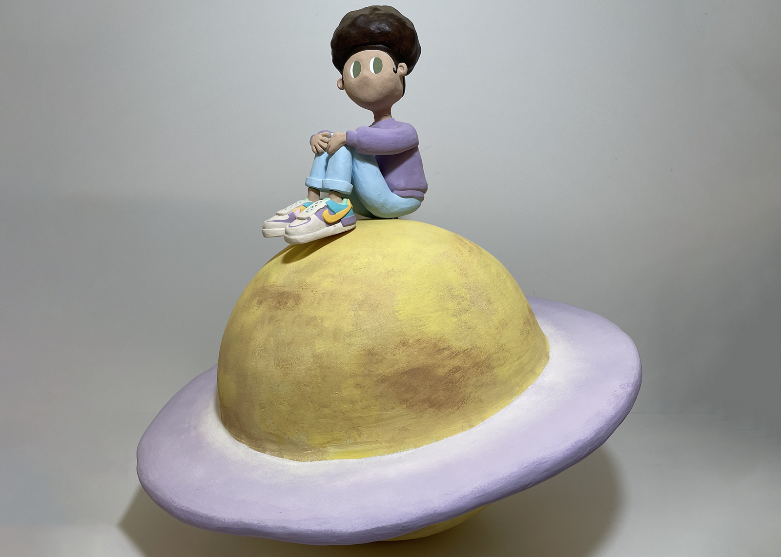 student artwork of Clay figure sitting on Saturn