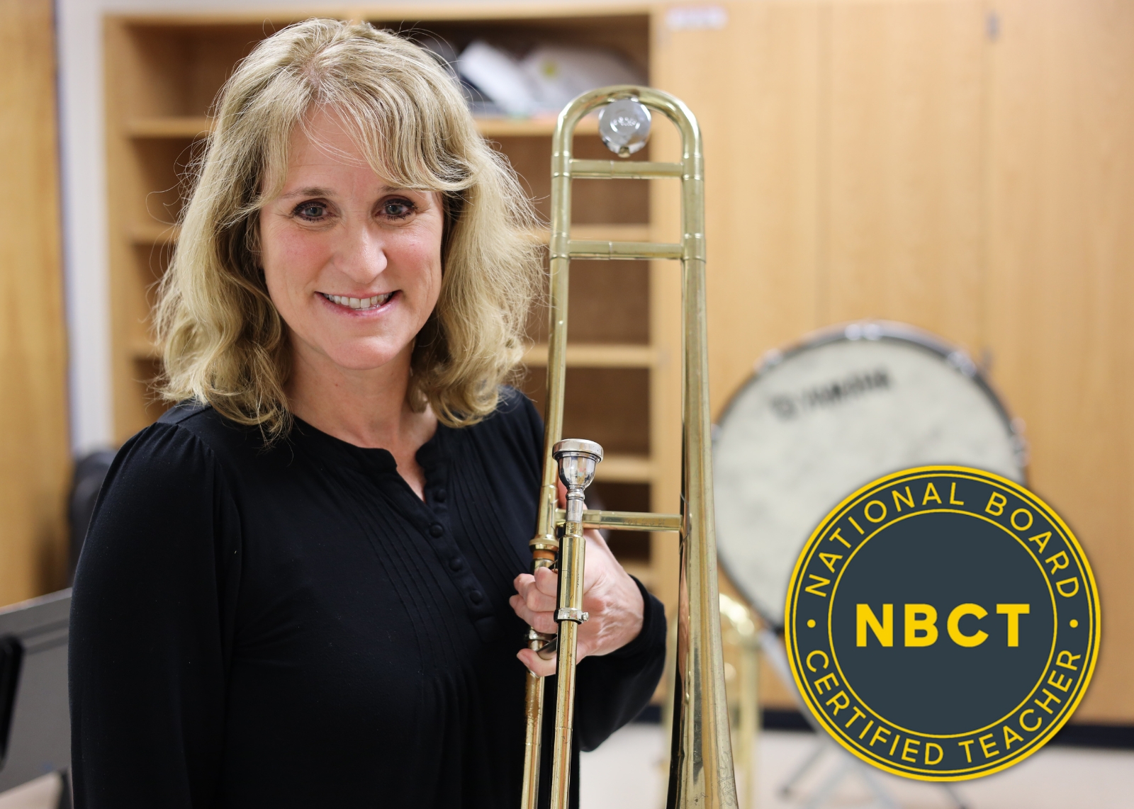 music teacher smiling holding a trombone