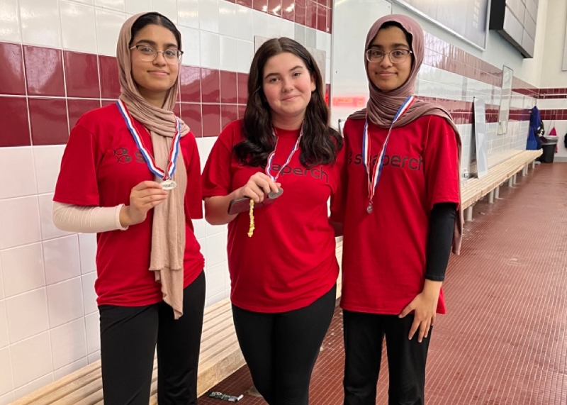 Three students with red shorts and medals around their necks