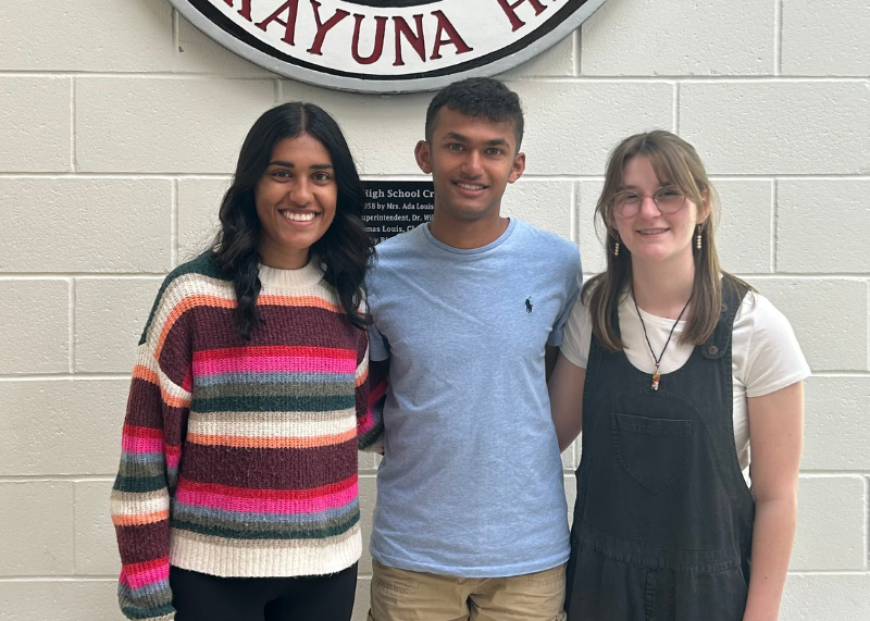 Three students stand together smiling