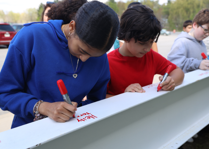 Two students sign beam