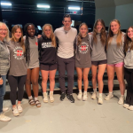 Stephen Hill posing with several students wearing grey clothing