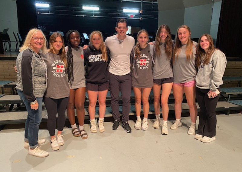 Stephen Hill posing with several students wearing grey clothing