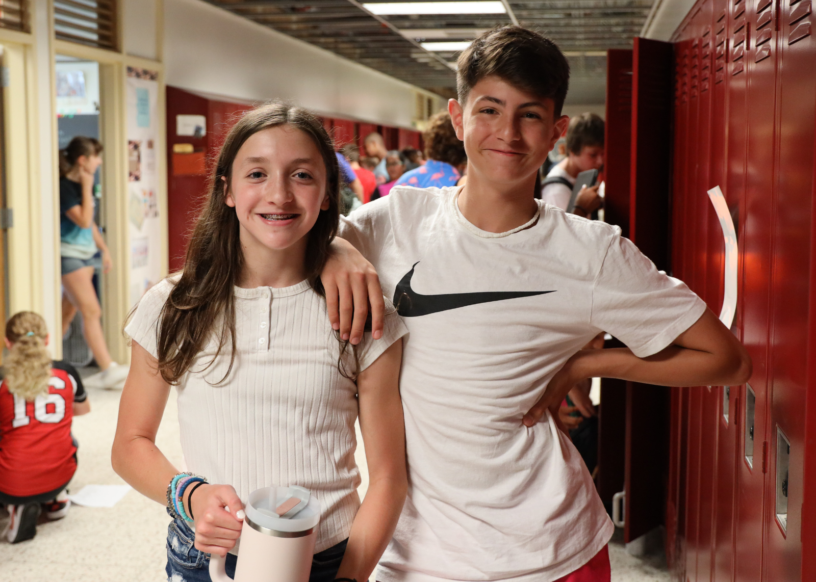 students in middle school hallway smiling