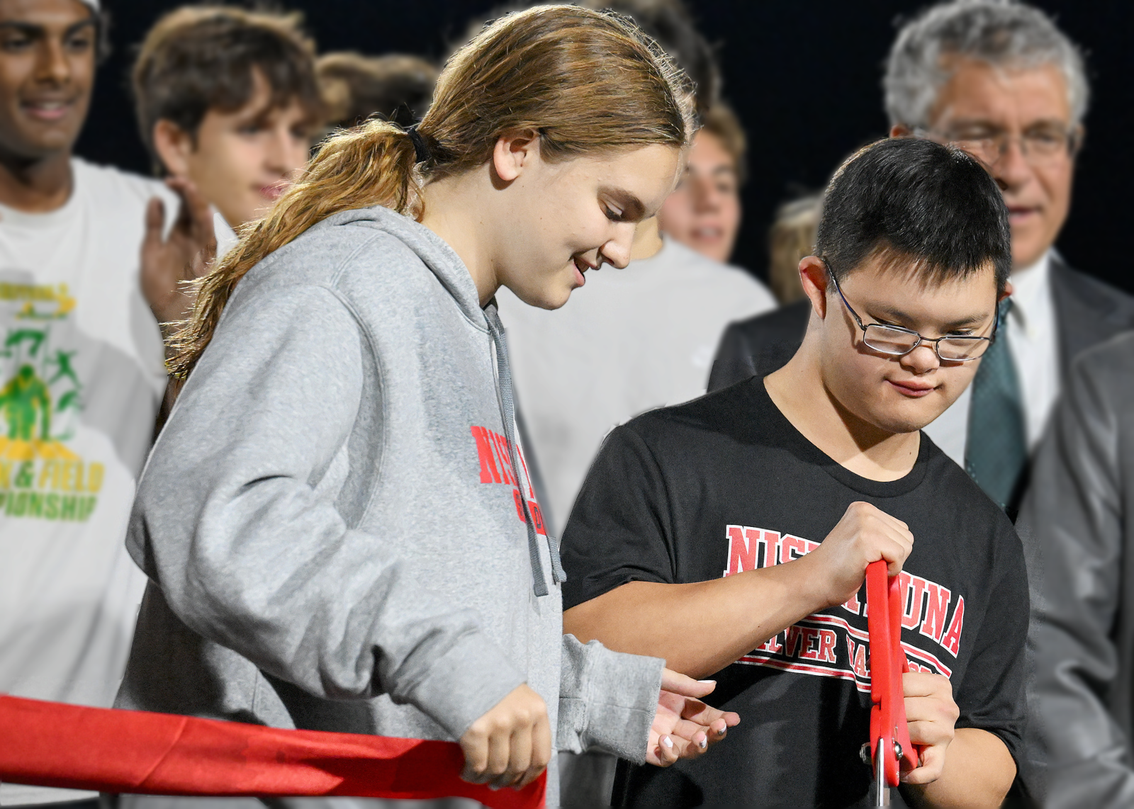 student athletes cutting ribbon on field