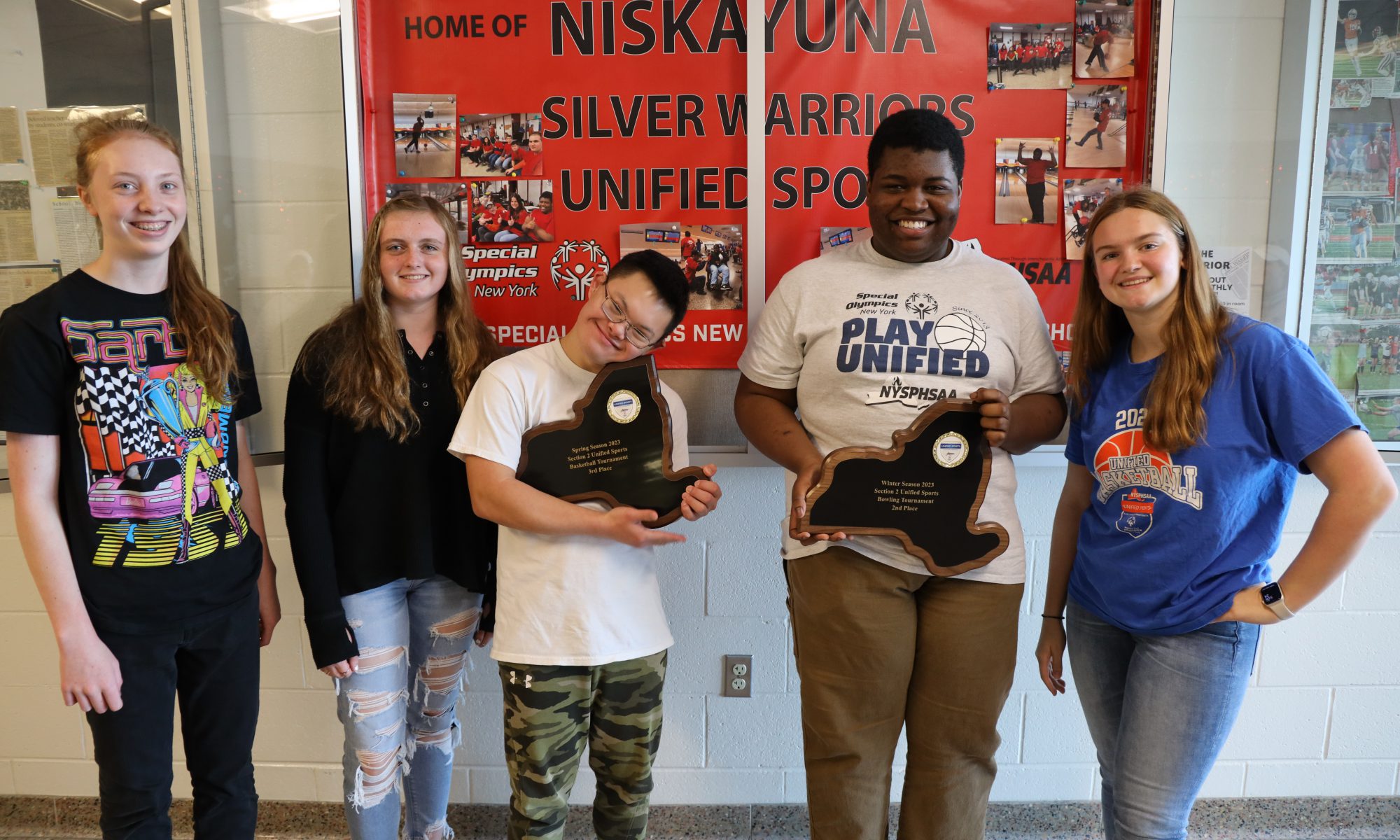 Unified sports teammates pose with plaques.