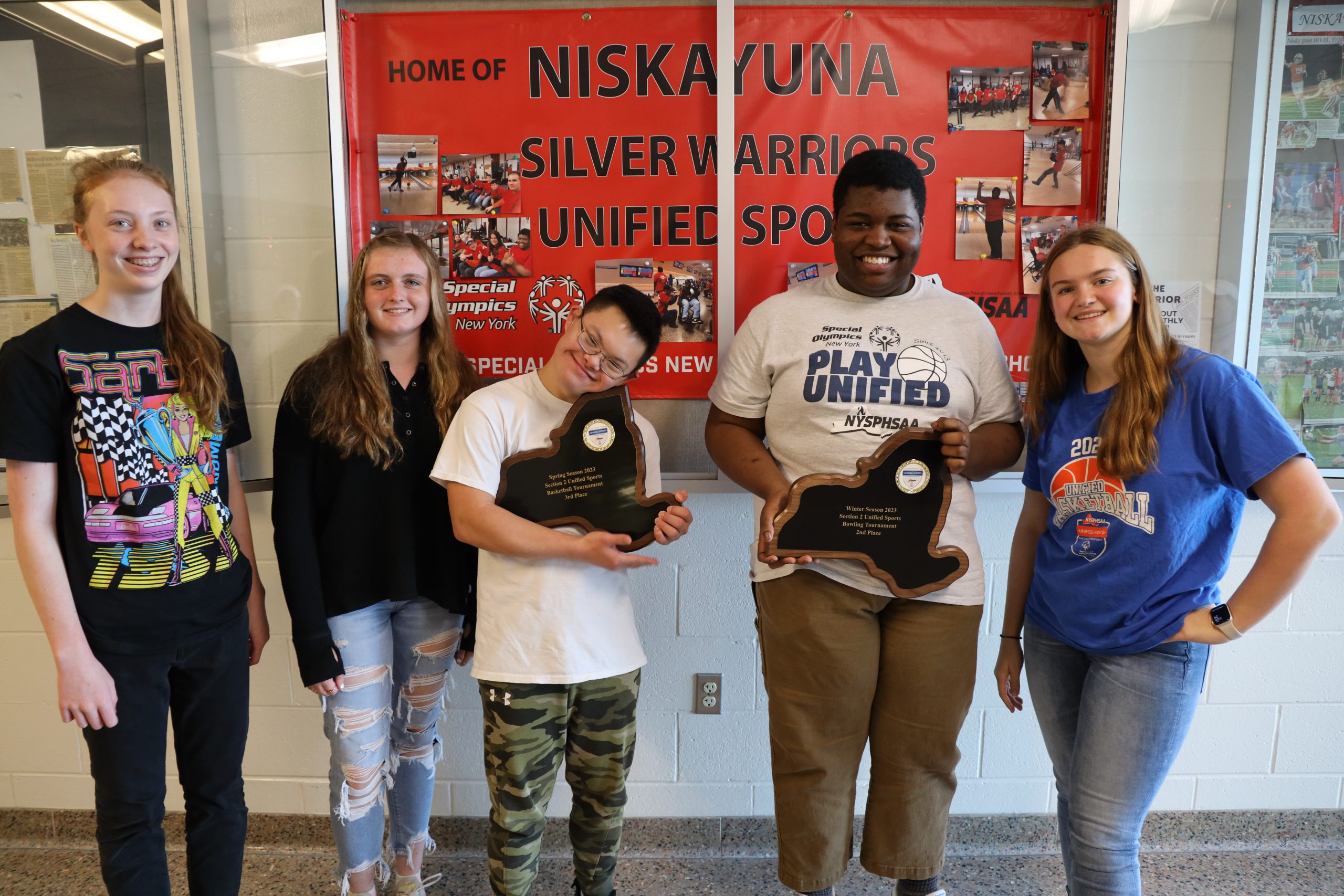 Unified sports teammates pose with plaques.