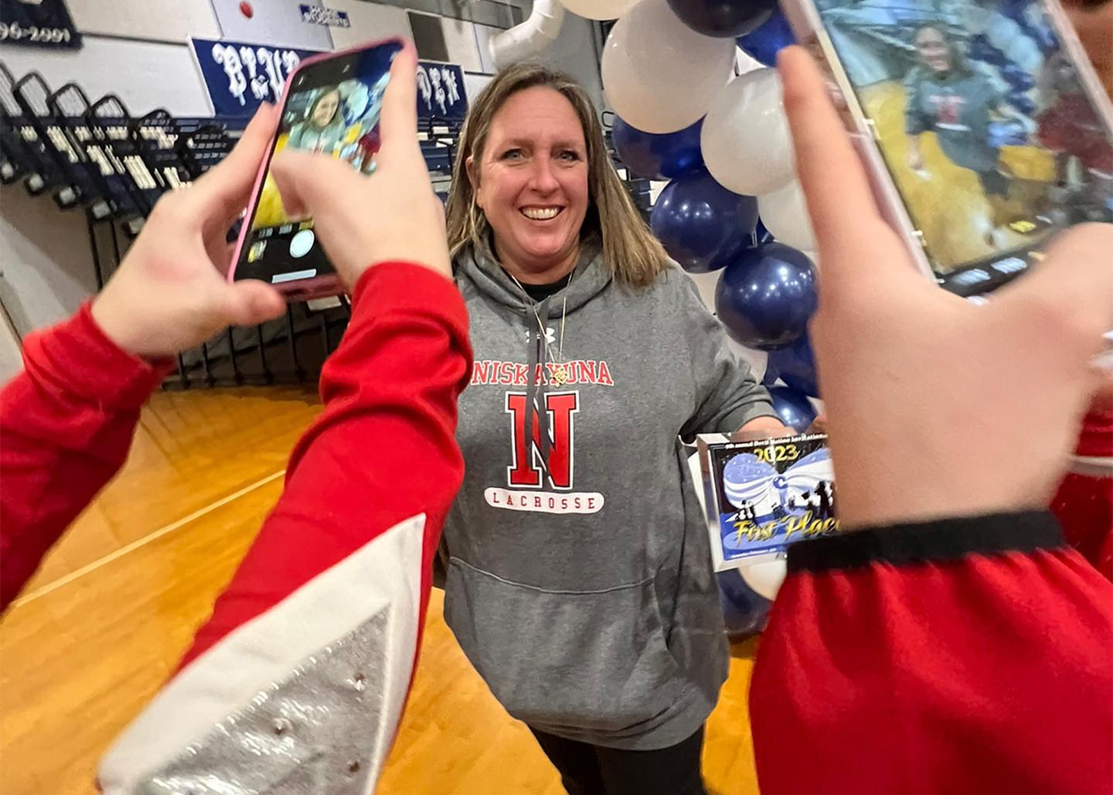 cheer coach with students taking photos in foreground