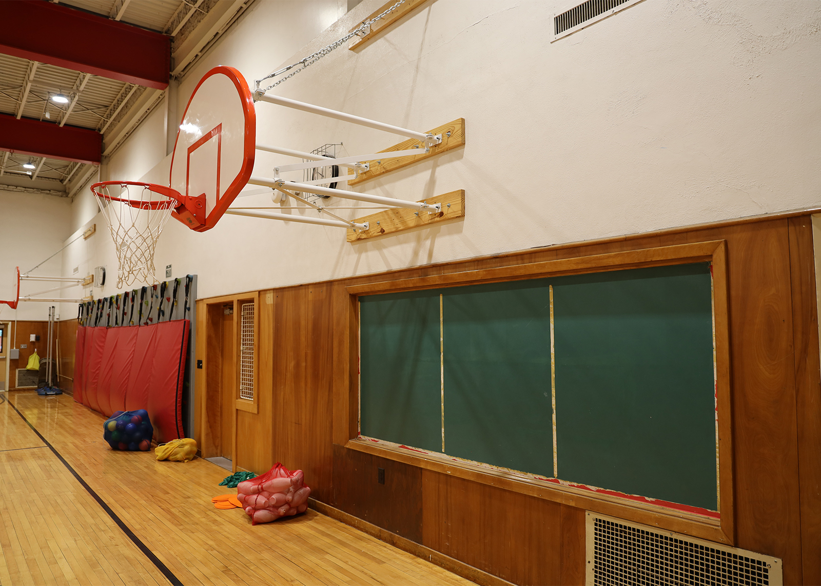 outdated gymnasium with basketball hoop and chlakboard