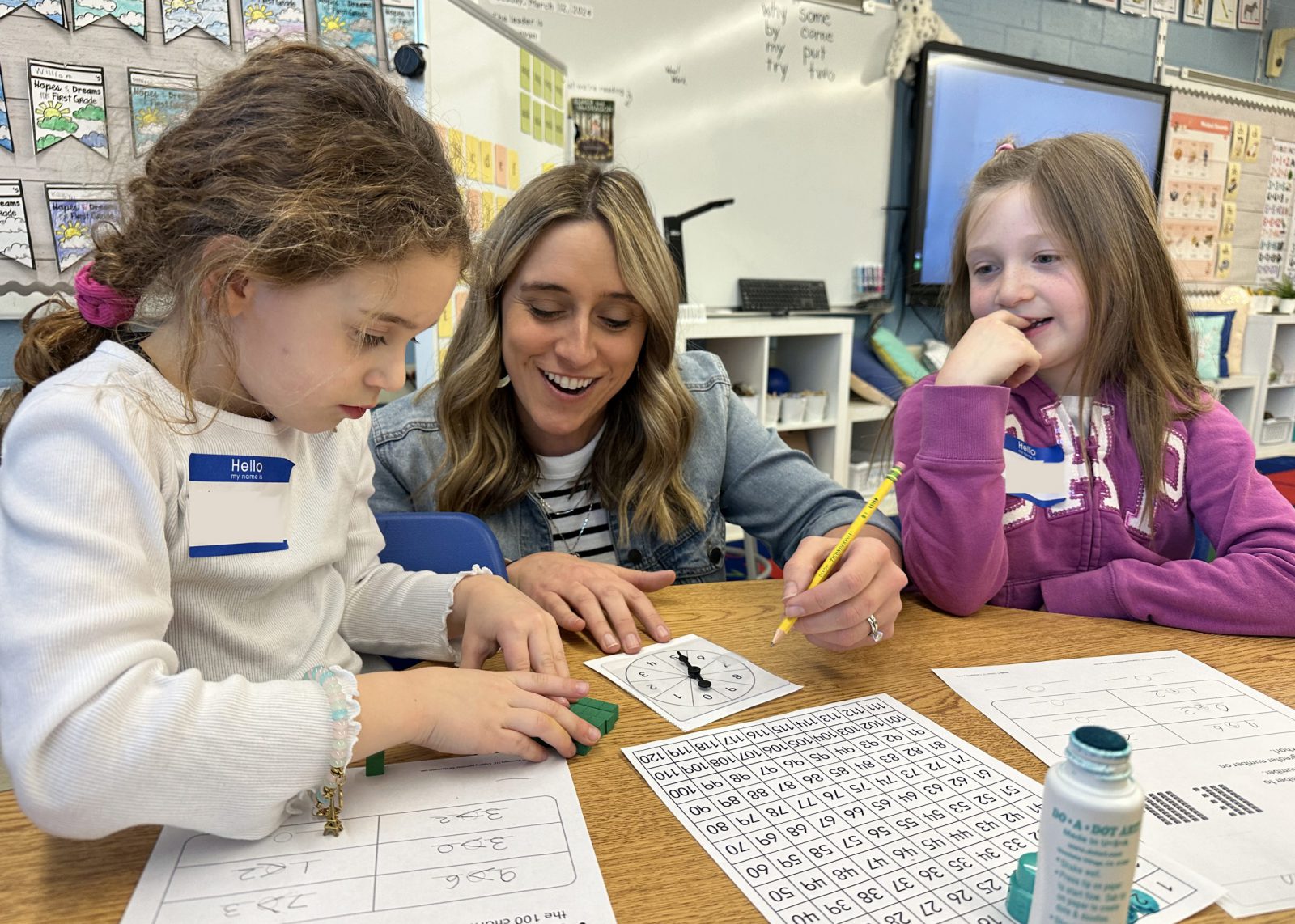 first grader teacher helping students with math