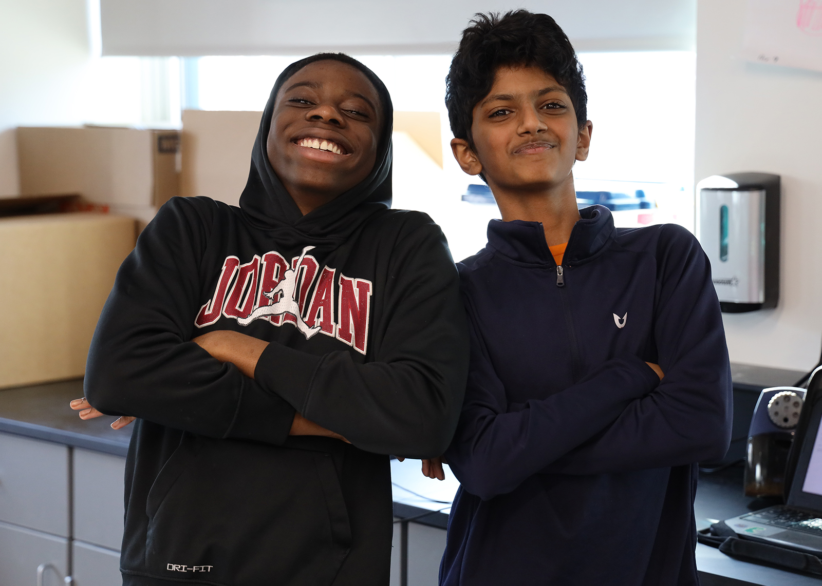 two students cross arms and smile for the camera