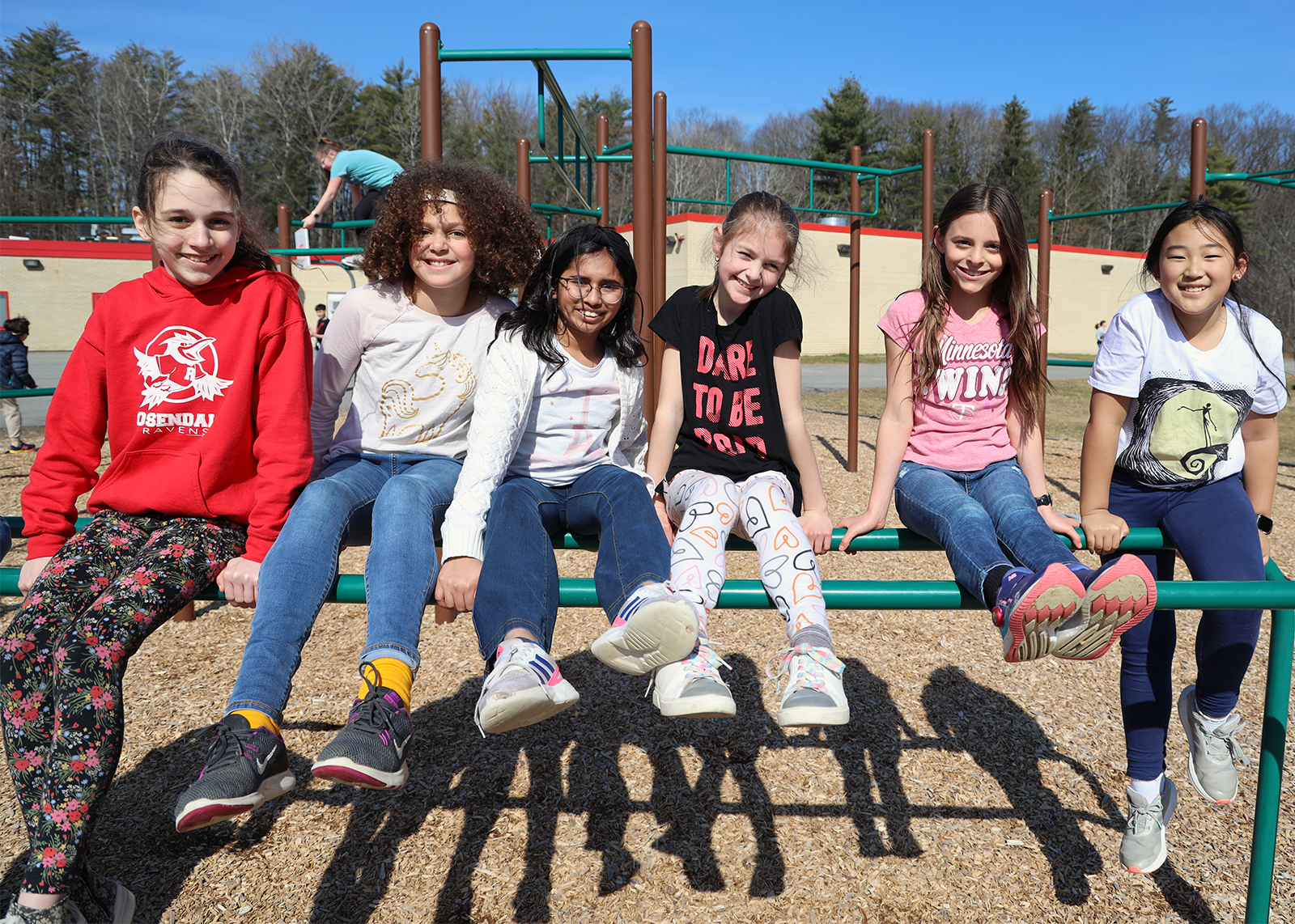 students balancing on playground bars and smiling