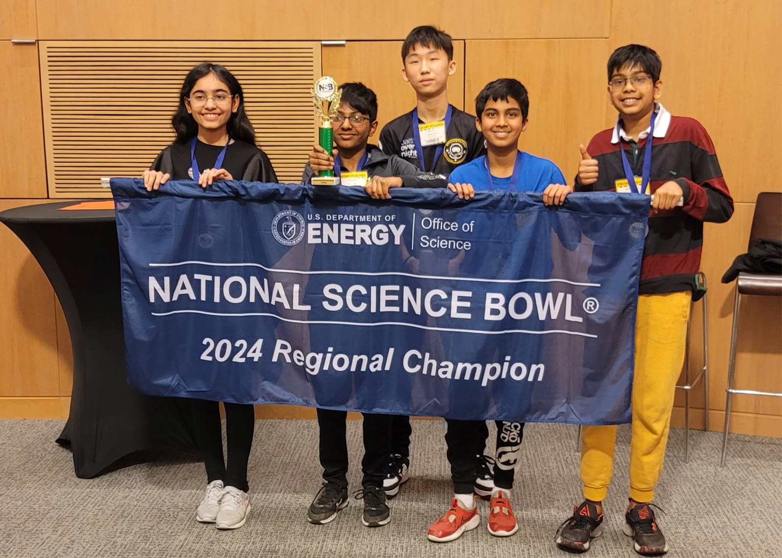 Five students holding National Science Bowl banner