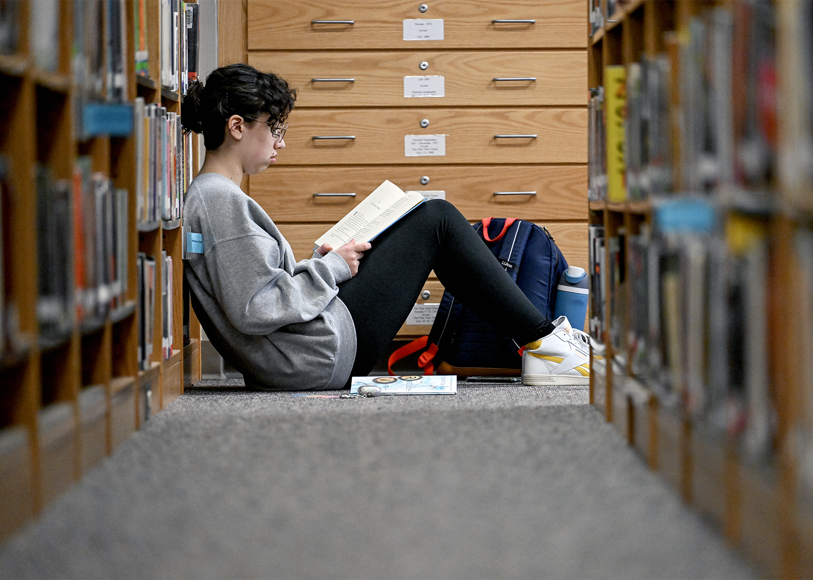 student in library leaning on bookcases