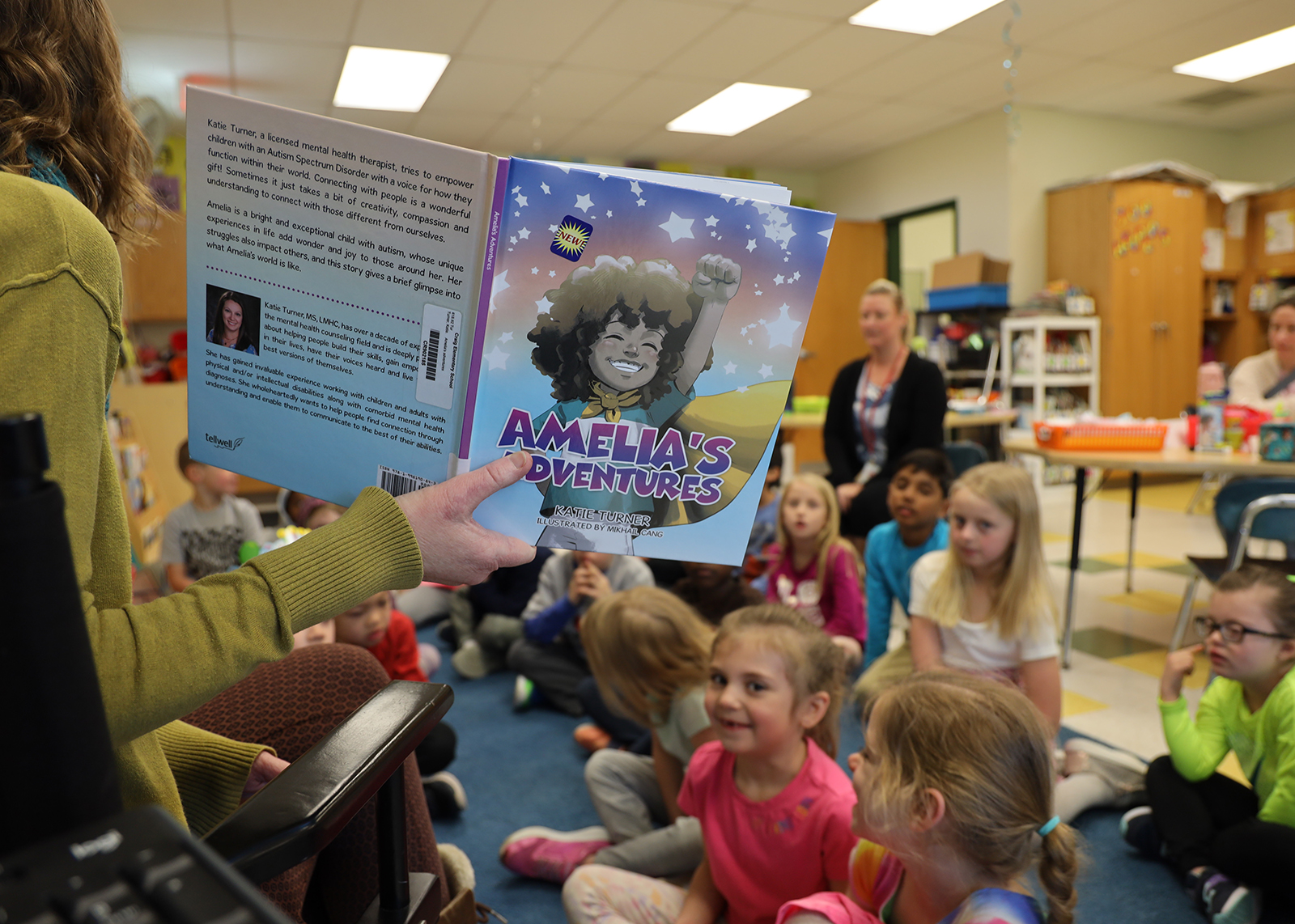 A teacher reads Amelia's Adventures to a group of students seated on the floor