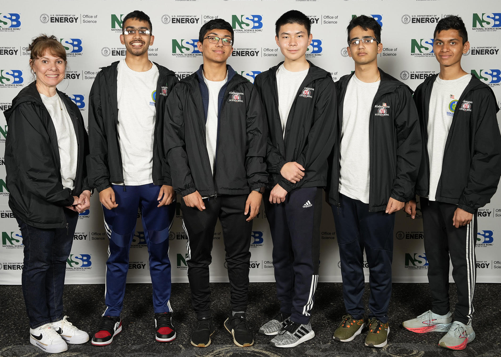 Five students pose in front of a NSB wall with a teacher