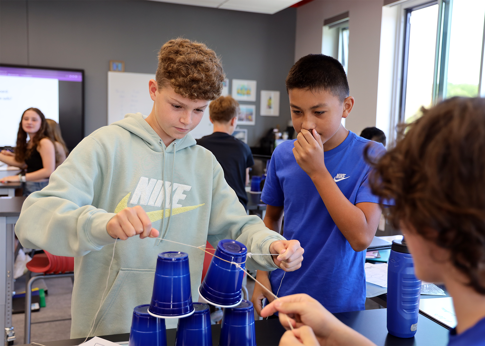 students working on science project with cups and string