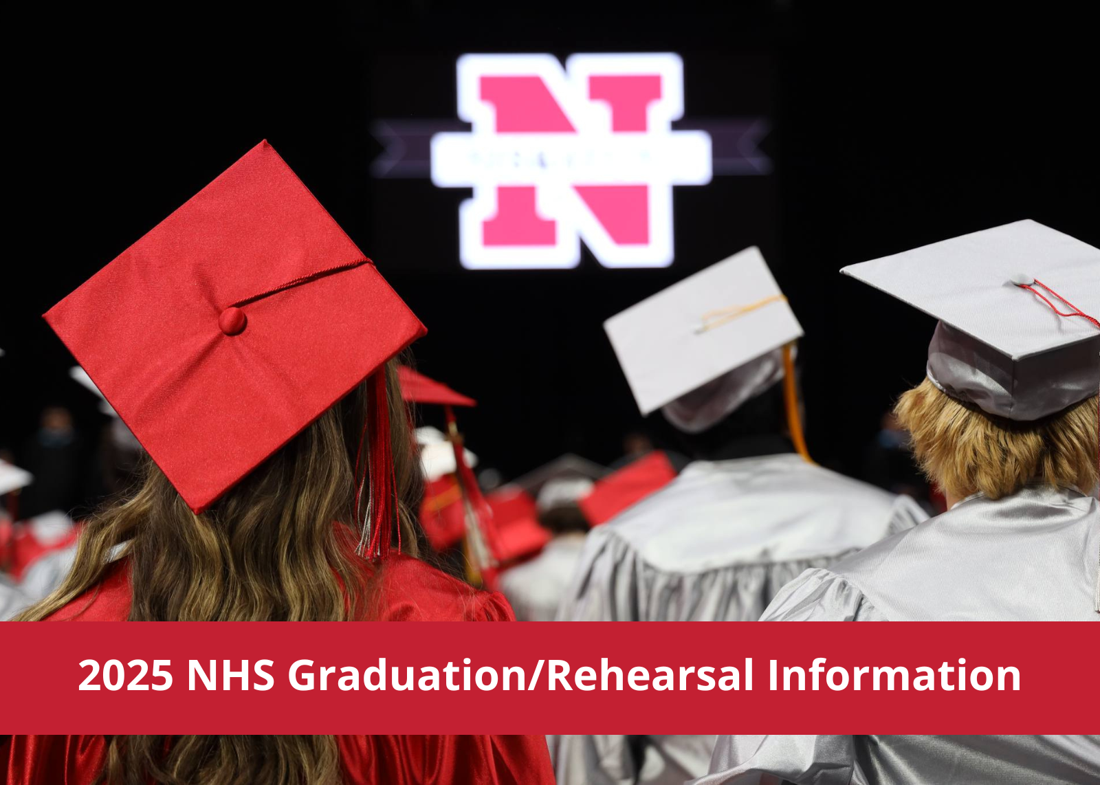 View from behind graduates in caps and gowns looking toward a stage with Niskayuna logo in background.