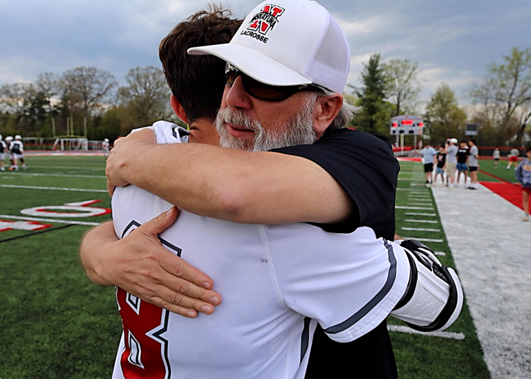 coach hugs lacrosse player after milestone win