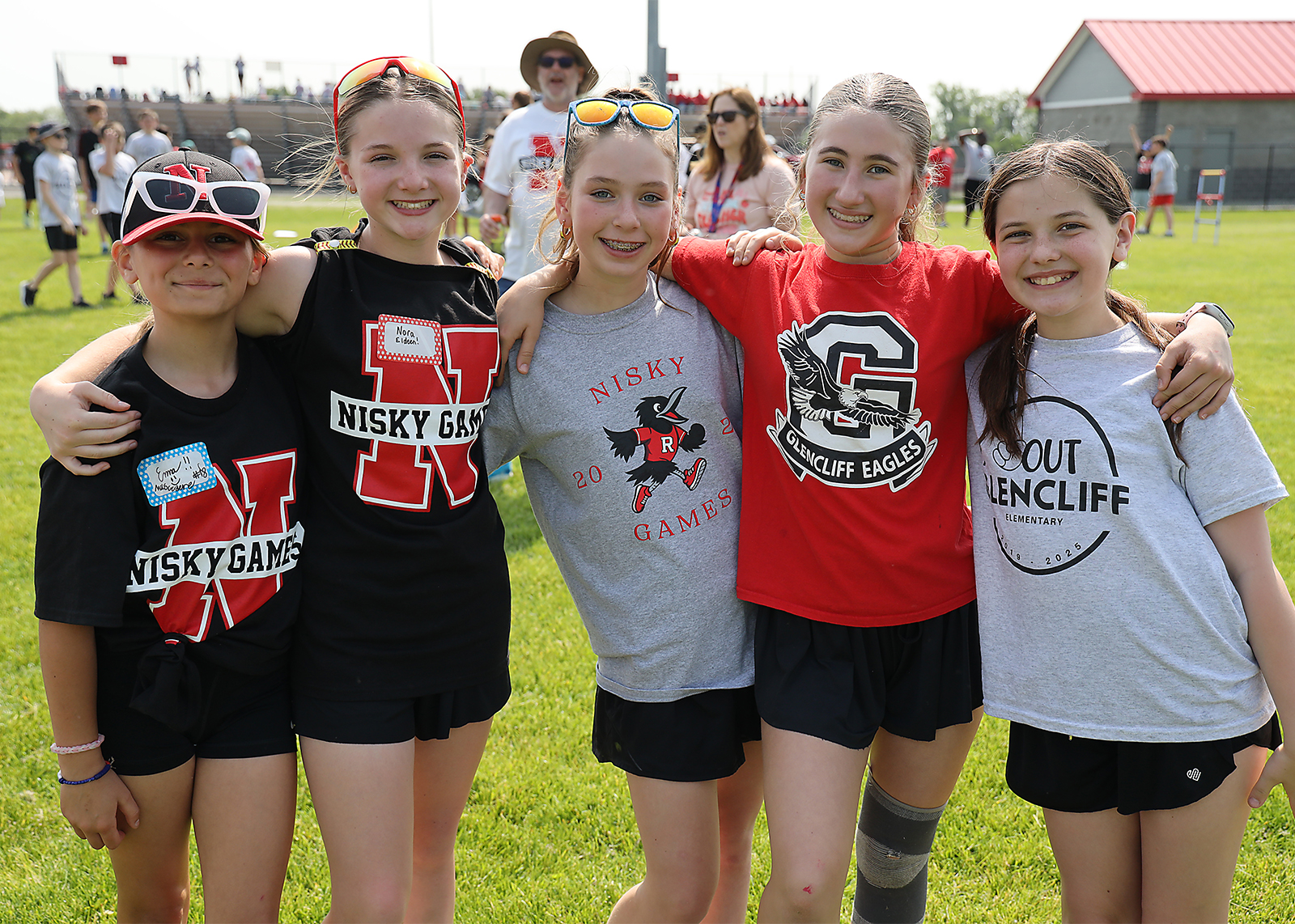 group of fifth graders smiling for camera with arms around each other