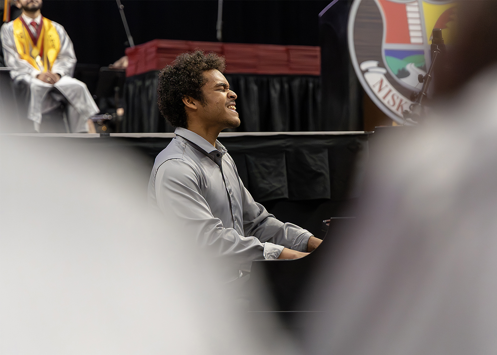 graduate plays piano during ceremony