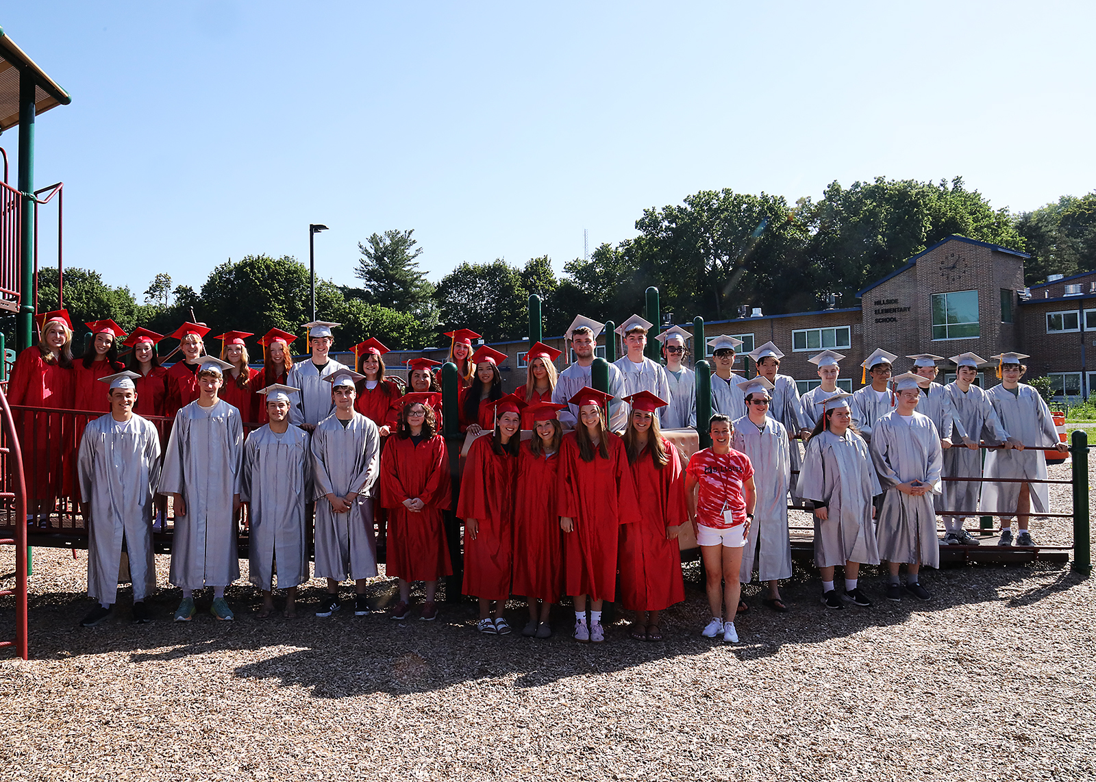 groupd of seniors in caps and gowns on playground