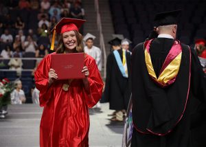 graduate holding up diploma and posing