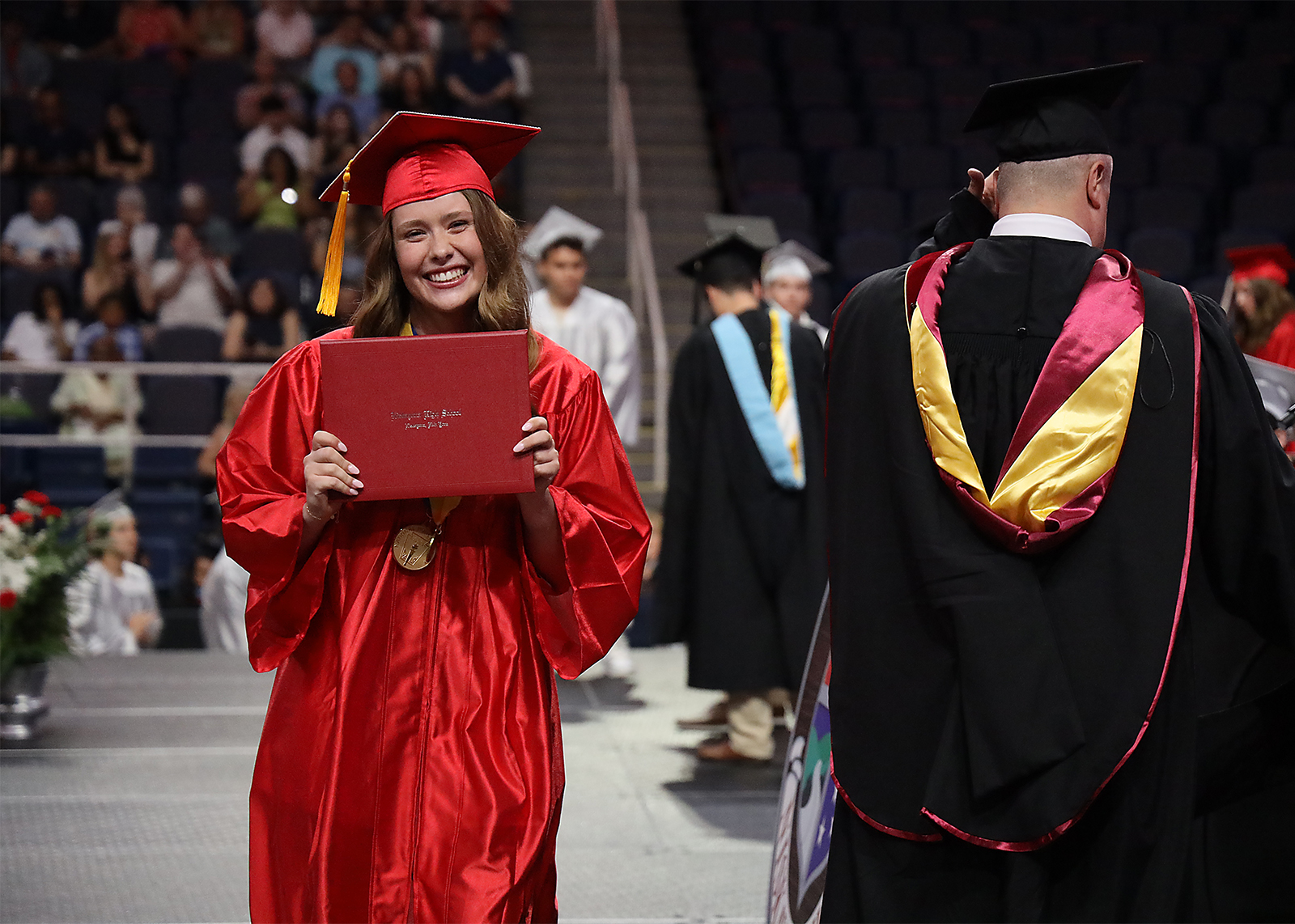 graduate holding up diploma and posing