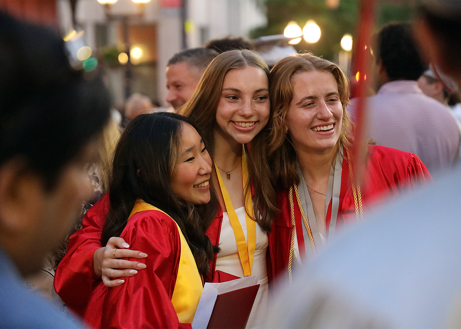 three graduate friends group together and smile