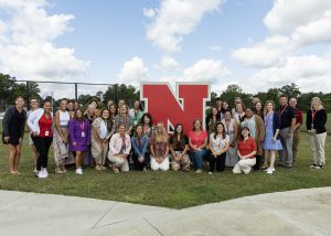 group of new staff member smiling in front of N statue